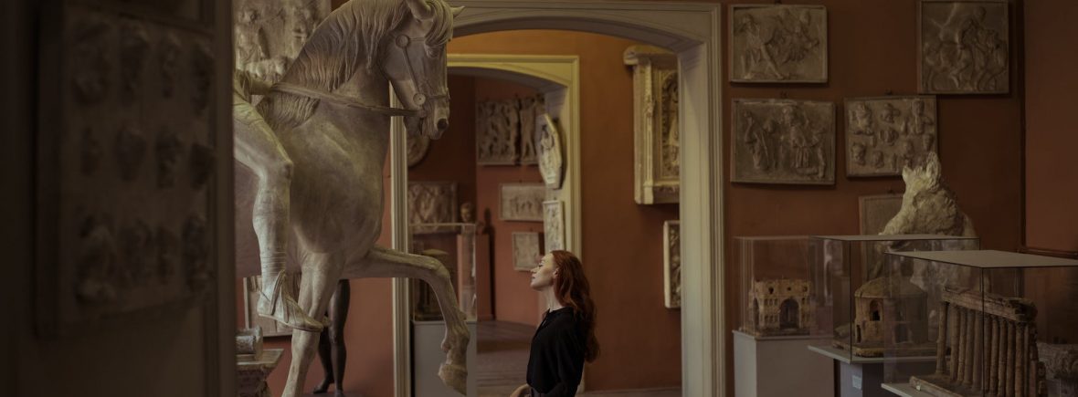 woman looking at a horse sculpture in a museum